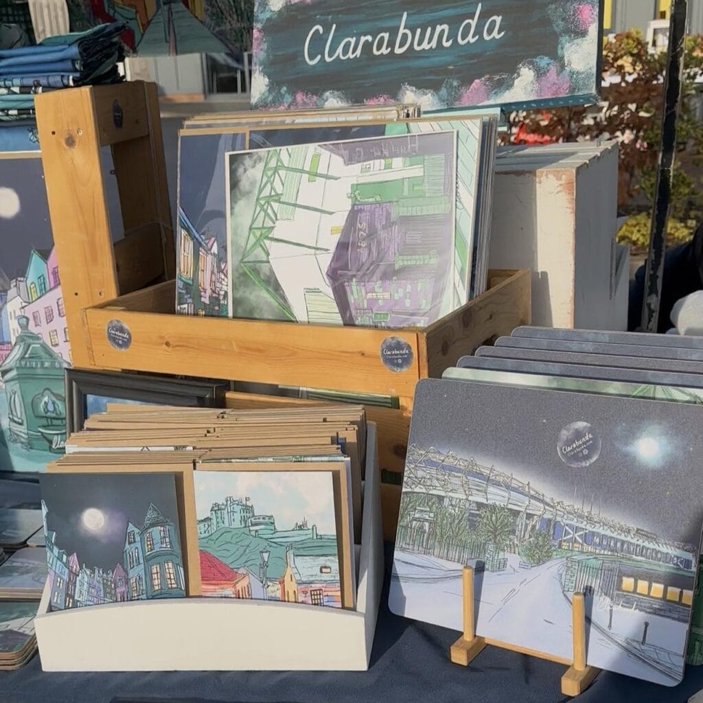 Display stand of illustrated postcards and prints with urban and nighttime scenes at Roswell Market, labeled Clarabunda at the top.