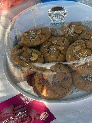 A glass cake stand with a lid displays cookies topped with nuts and sugar, styled beautifully beside an Elementor-themed business card.